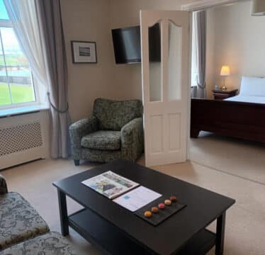 Deluxe Suite at The Walter Raleigh Hotel with a living room and large double bed.