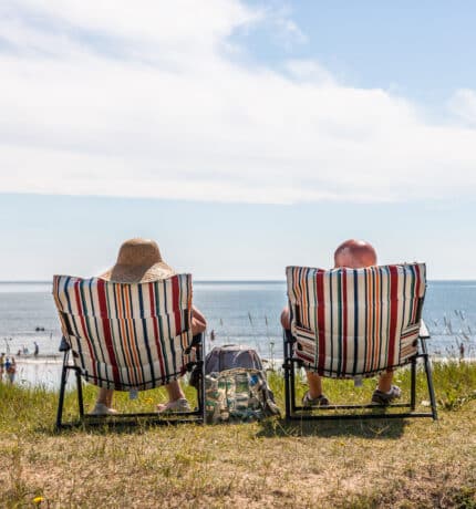 a couple sunbath on deckchairs at the seafront in Claycastle
