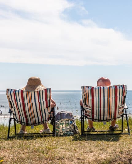 a couple sunbath on deckchairs at the seafront in Claycastle