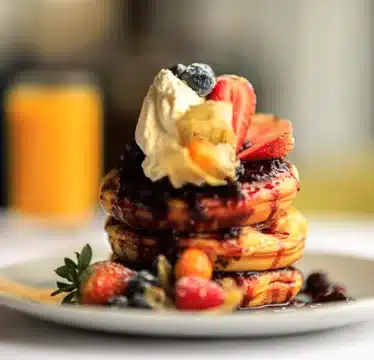 Stack of pancakes with cream and berries