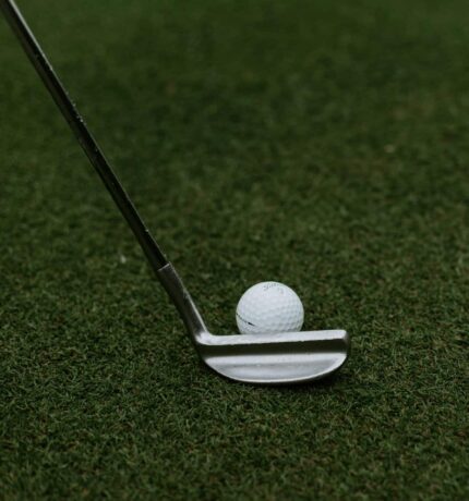 Golf club and golf ball on green pitch
