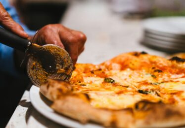 Chef cutting pizza with pizza cuttter