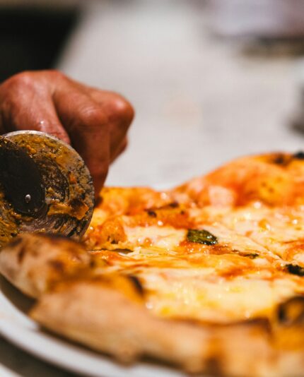 Chef cutting pizza with pizza cuttter